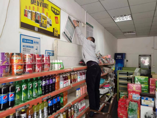 圖為專賣人員為零售戶懸掛許可證