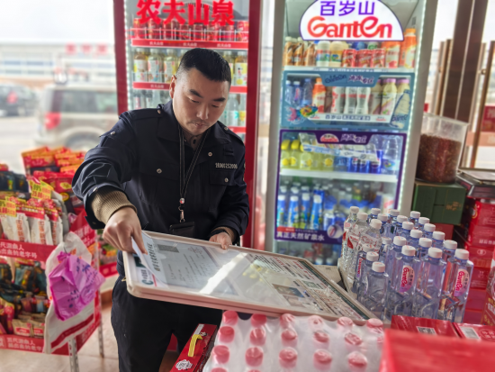 圖為稽查員為新辦證零售戶掛許可證.png