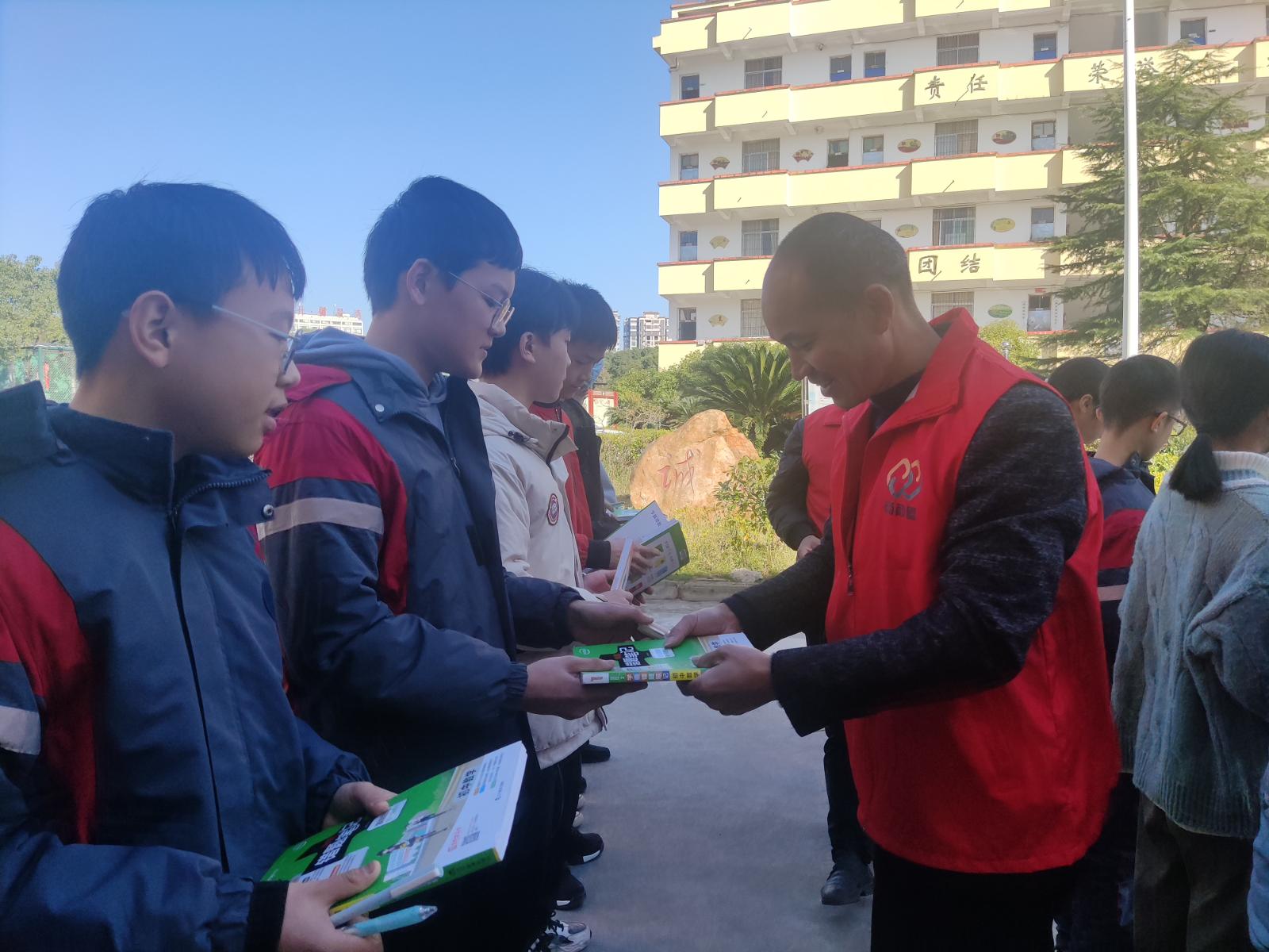 圖為志愿者向困難學生贈送書籍.jpg