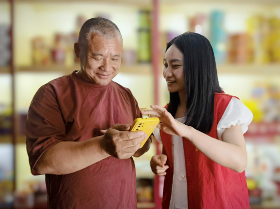 圖為志愿者指導(dǎo)零售戶網(wǎng)上延續(xù)