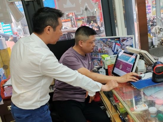 圖為客戶經(jīng)理借助云POS幫助客戶分析熱銷商品數(shù)據(jù)(彭浩)