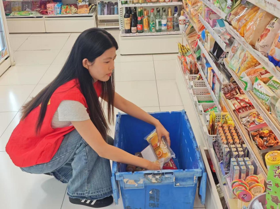 圖為志愿服務者幫忙陳列貨架
